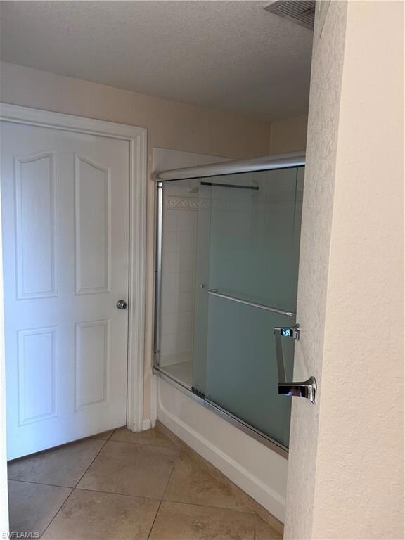 Bathroom featuring light tile patterned flooring and a textured ceiling
