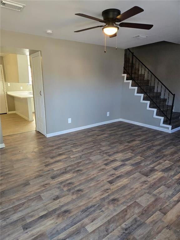 Empty room featuring stairway, dark wood-type floo