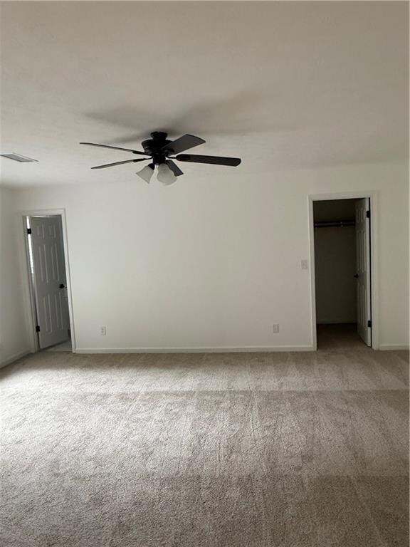 Empty room featuring light colored carpet and a ceiling fan