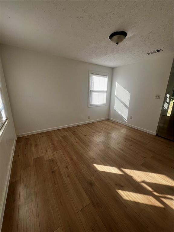 Spare room featuring wood-type flooring and a textured ceiling