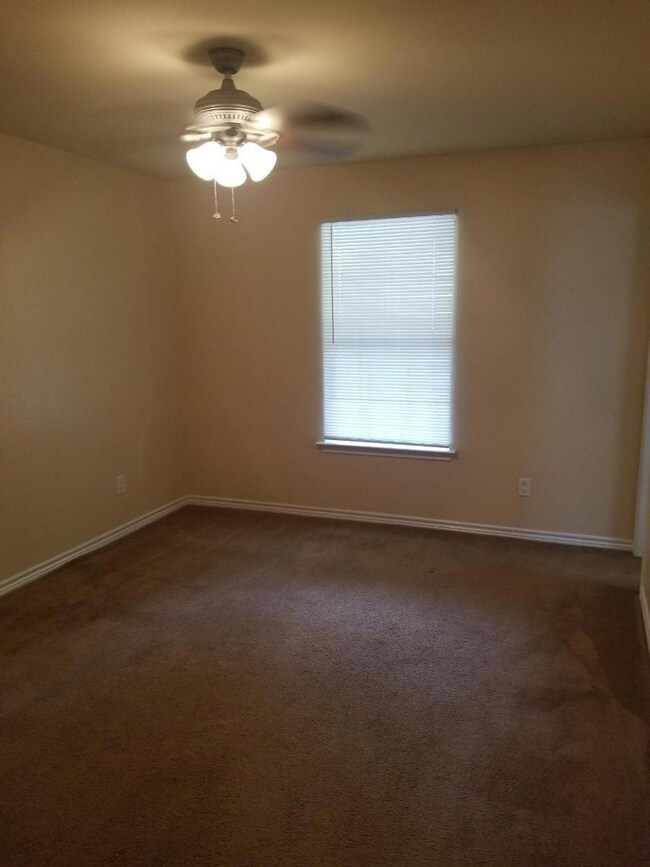 Empty room with dark colored carpet and ceiling fa