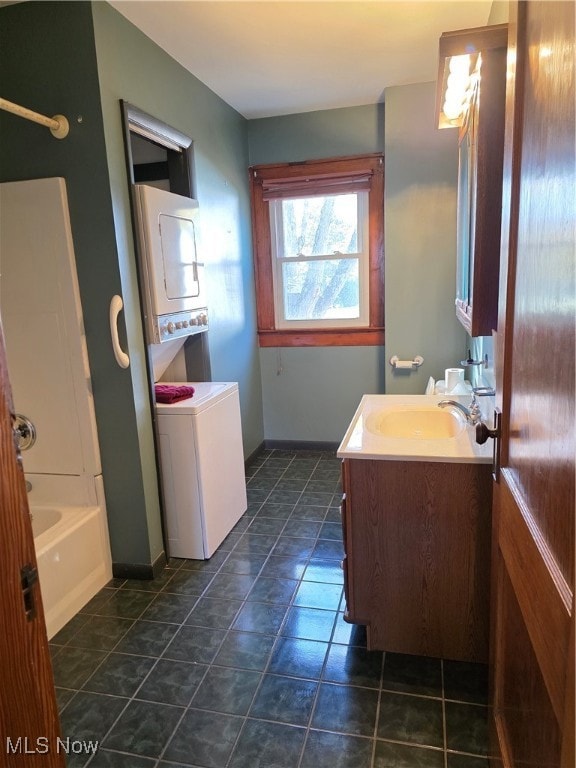 Full bath featuring vanity, stacked washer / drying machine, and bathing tub / shower combination
