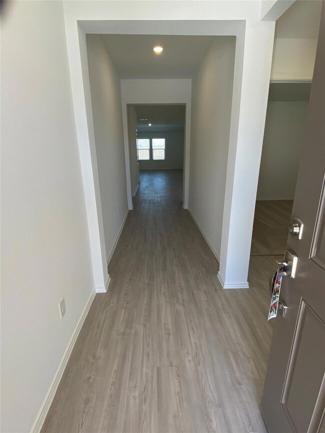 Hallway with light wood-style floors and baseboar
