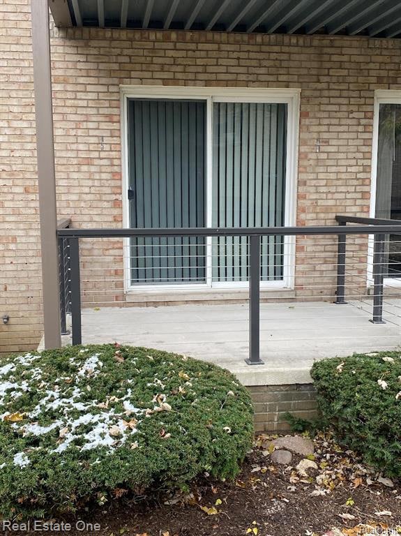 Doorway to property featuring brick siding and a deck