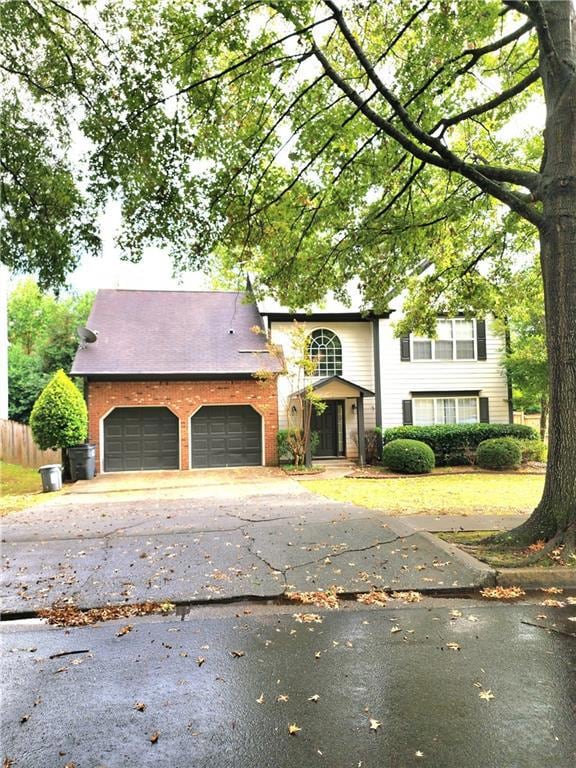 View of front facade with driveway, brick siding, and a garage