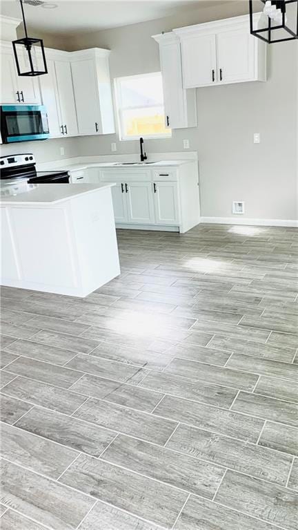 Kitchen featuring pendant lighting, appliances with stainless steel finishes, and white cabinetry