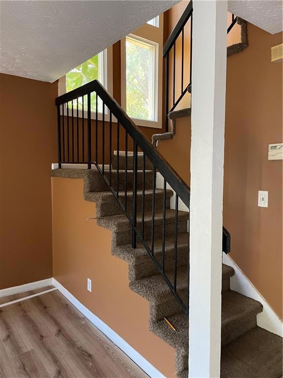 Stairway with a textured ceiling and hardwood / wo