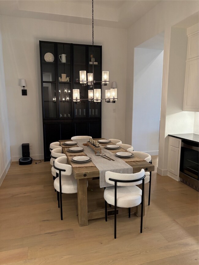 Dining room with light wood-type flooring, wine cooler, and a chandelier