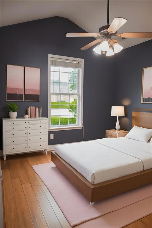 Bedroom with vaulted ceiling, light wood-style flooring, and a ceiling fan