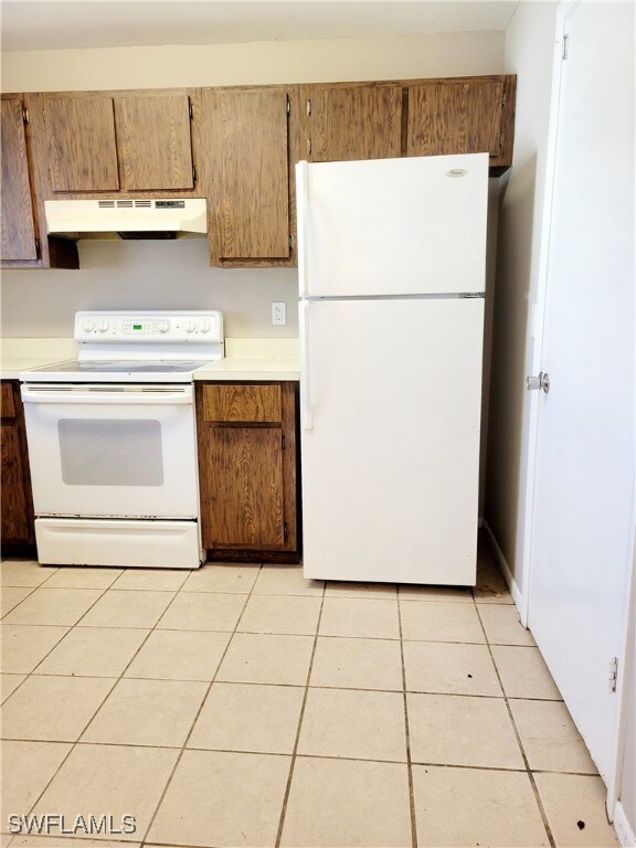 Kitchen featuring light tile patterned floors and white appliances
