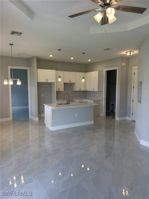 Kitchen featuring pendant lighting, a kitchen island with sink, recessed lighting, ceiling fan, and light marble finish floors