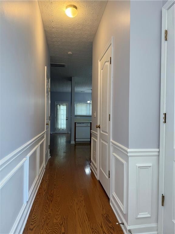 Hall with dark wood-style flooring, a textured cei