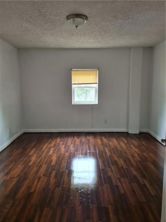 Empty room featuring hardwood / wood-style floors and a textured ceiling