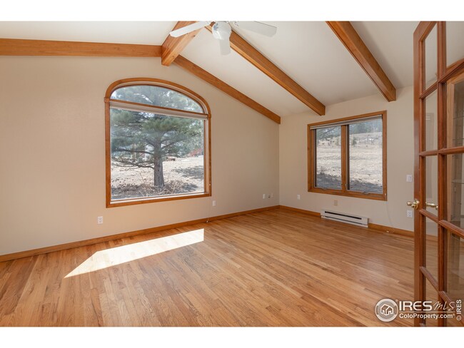 Primary bedroom with beamed cathedral ceiling and elegant picture window
