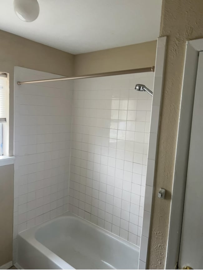 Bathroom with shower / tub combination and a textured wall