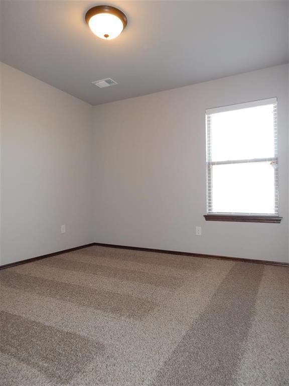 Unfurnished room featuring visible vents, baseboar