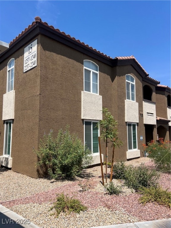 View of property exterior featuring stucco siding and a tiled roof