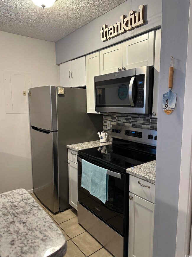 Kitchen with light stone countertops, a textured c
