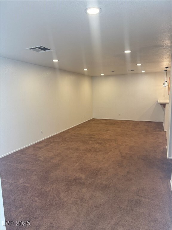 Finished basement with dark carpet and recessed li