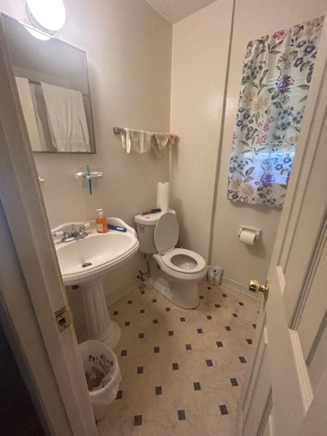Half bath featuring toilet and baseboards