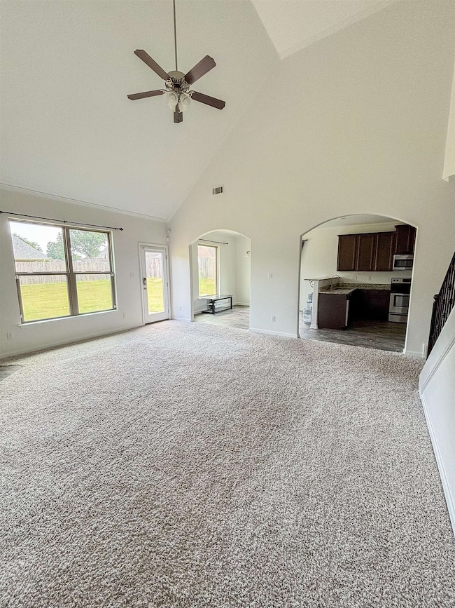 Unfurnished living room with arched walkways, high
