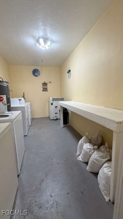 Washroom featuring concrete floors, separate washer and dryer, and water heater