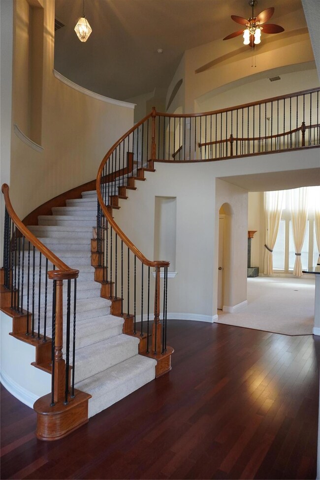 Stairs featuring dark wood-type flooring, ceiling fan, and a towering ceiling