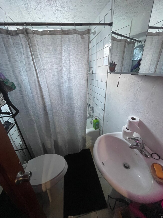 Full bathroom featuring shower / bath combination with curtain and a textured ceiling