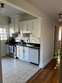 Kitchen with white cabinetry, stainless steel electric stove, white dishwasher, and sink