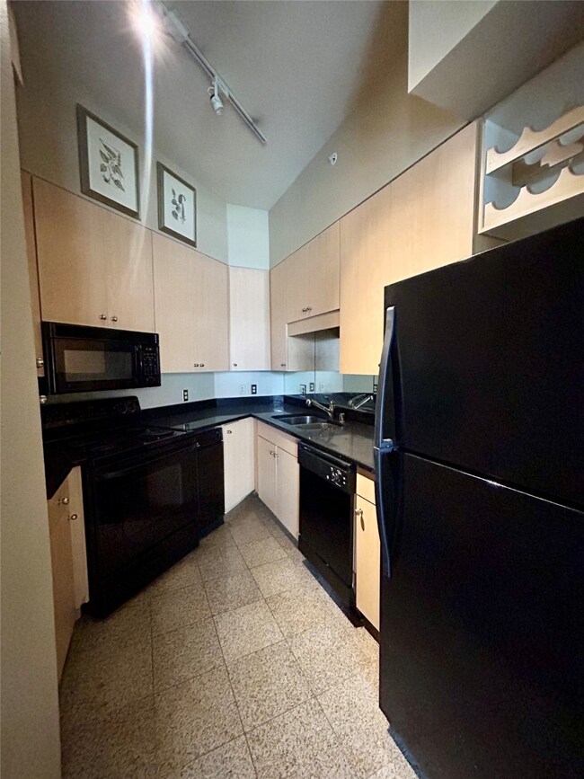 Kitchen featuring black appliances, dark countertops, and track lighting