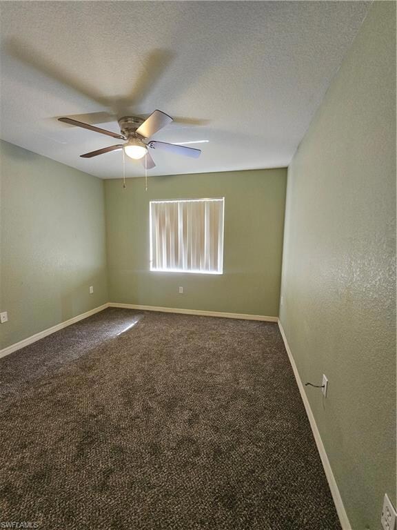 Unfurnished bedroom with baseboards, visible vents, dark colored carpet, and a closet