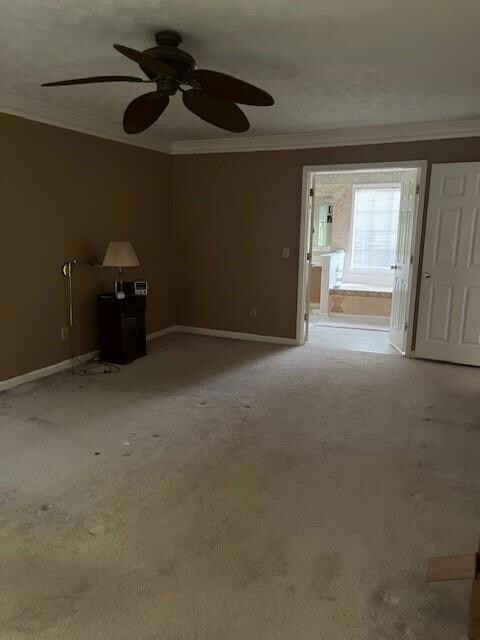 Carpeted spare room with ornamental molding, baseboards, and ceiling fan