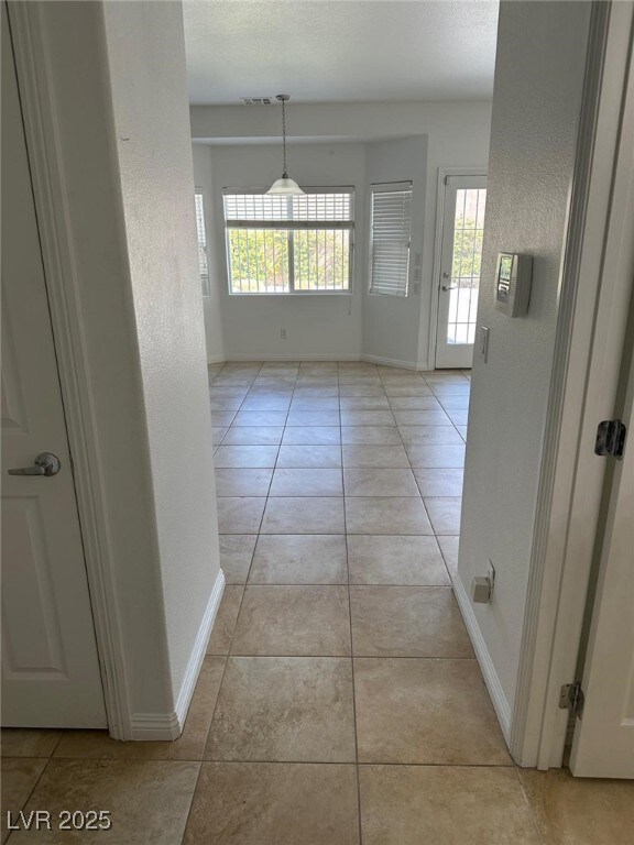 Corridor with baseboards, light tile patterned flo