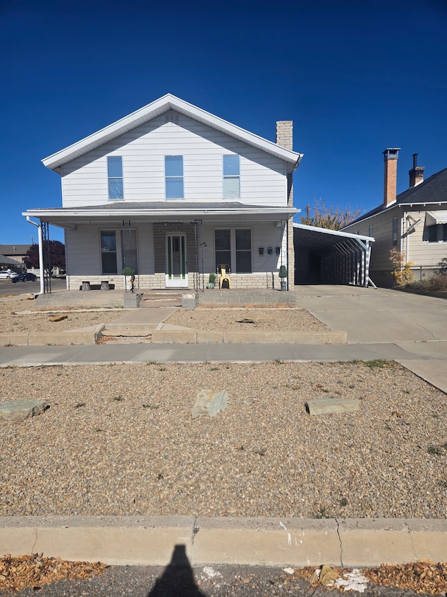View of front of home featuring covered porch, driveway, a carport, and a chimney