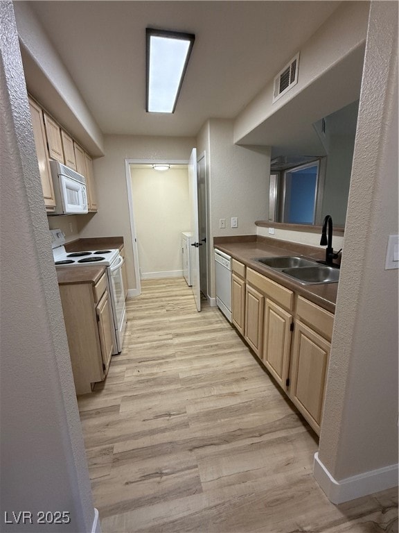 Kitchen featuring light brown cabinetry, range, light wood-style floors, dark countertops, and a textured wall