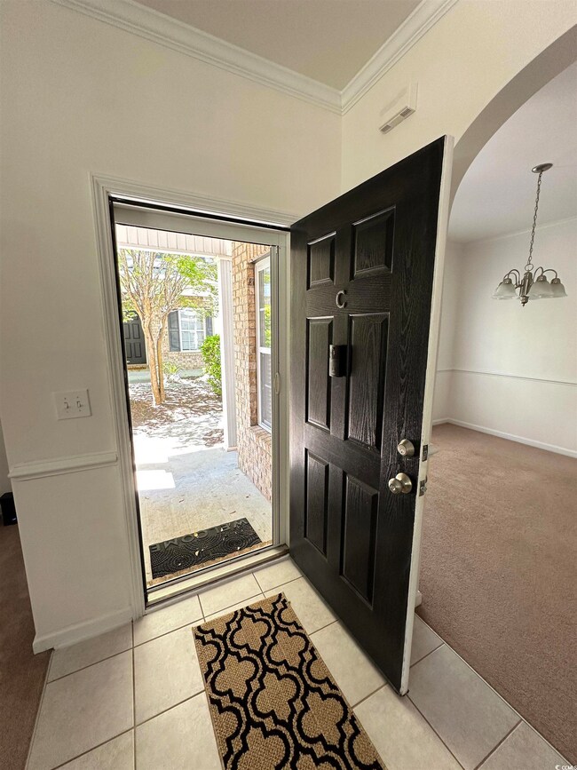 Foyer with an inviting chandelier, light tile patt