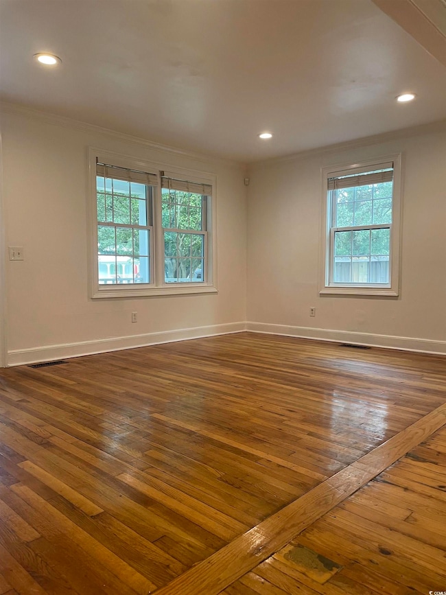 Empty room featuring dark wood-style floors, crown molding, and recessed lighting