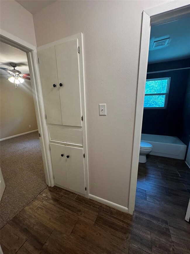 Corridor with dark wood-type flooring and baseboa