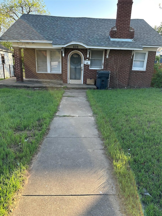 Ranch-style house with brick siding, a front lawn, and a chimney