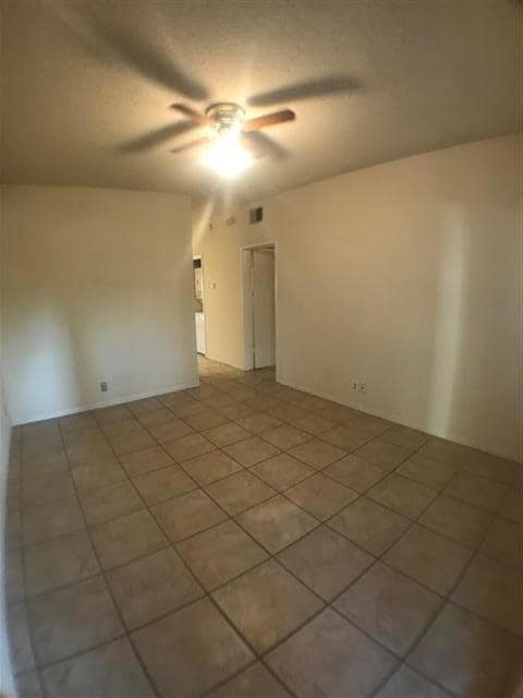Empty room with a ceiling fan and light tile patt