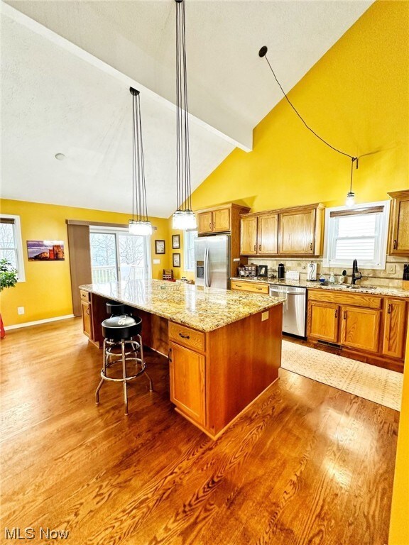 Kitchen with hardwood / wood-style flooring, stainless steel appliances, a center island, and hanging light fixtures