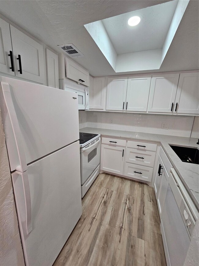 Kitchen with visible vents, white cabinets, range,