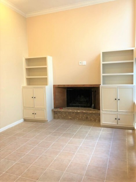 Spacious living room with high ceilings, built ins and fire place.