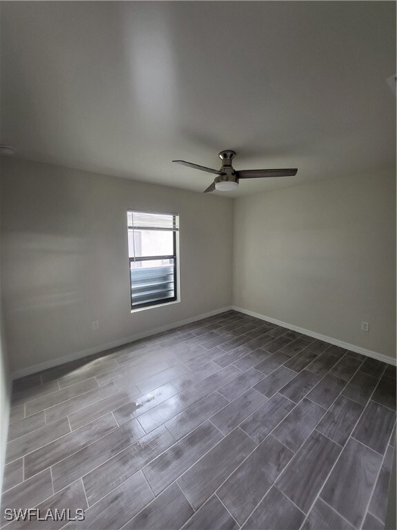 Empty room featuring baseboards, a ceiling fan, an