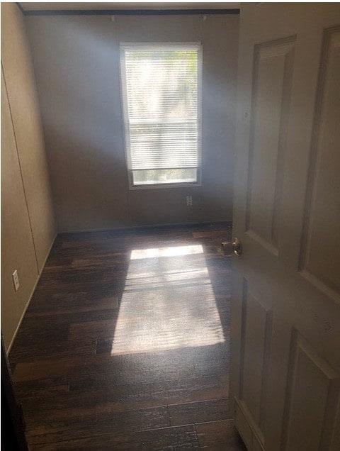 Unfurnished room featuring dark wood-type flooring