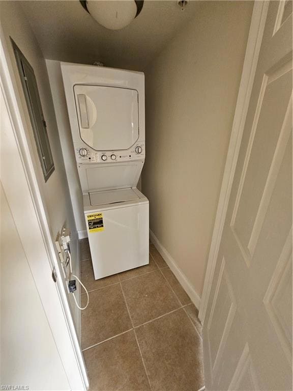 Laundry area featuring light tile patterned floors, stacked washing machine and dryer, and electric panel