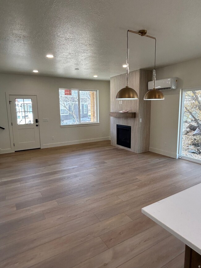 Unfurnished living room featuring plenty of natural light, a textured ceiling, a fireplace, light wood finished floors, and recessed lighting