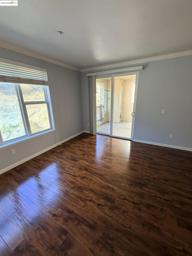 Unfurnished room with crown molding and dark wood-style flooring