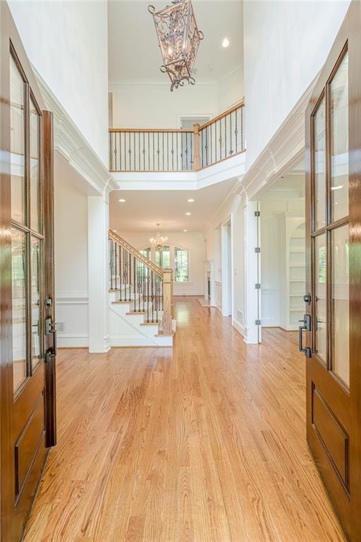 Foyer entrance with a chandelier, a towering ceiling, stairs, ornamental molding,