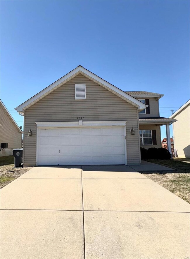 View of front of property featuring concrete driveway and an attached garage